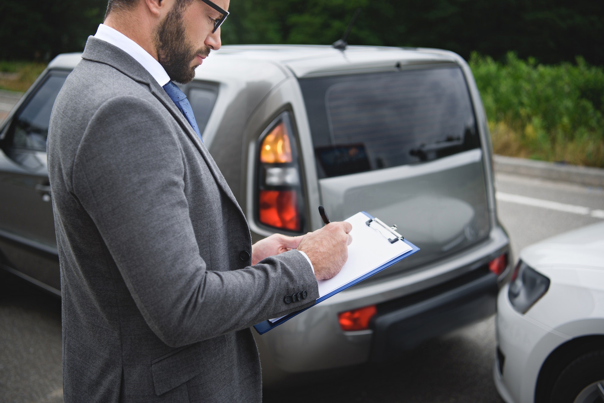 side-view-of-man-writing-something-to-car-insurance-after-car-accident.jpg
